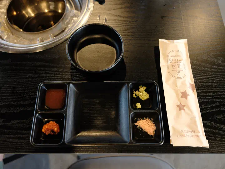 Fresh wasabi, seasoned salt, beef ssamjang, and barbecue sauce in a Korean dipping tray at Udam