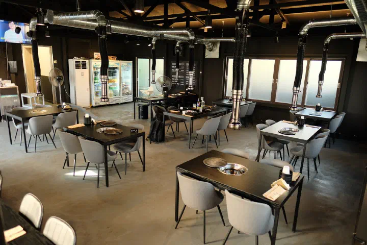 Dining tables and the self-serve drink fridge inside Udam Jeju Jungmun