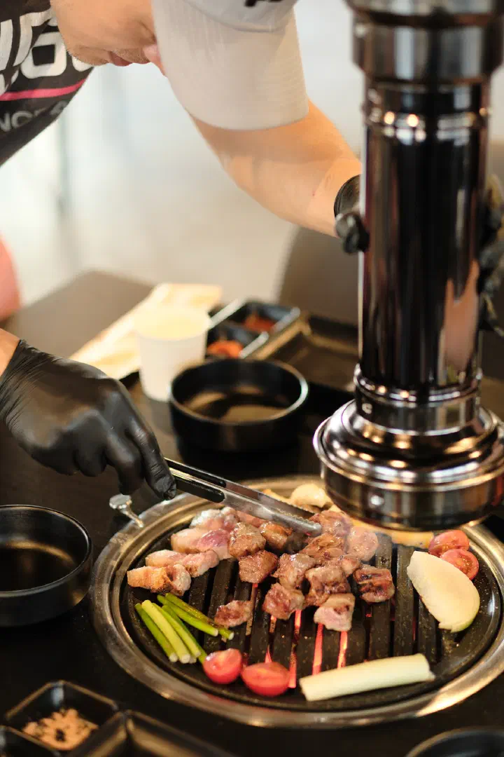The owner grilling black pork table-side for diners at Udam