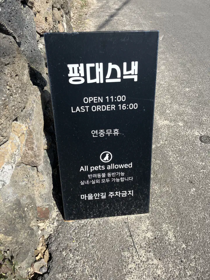 Pyeongdae Snack street sign - opens 11 a.m., pets welcome, no parking in the village lanes