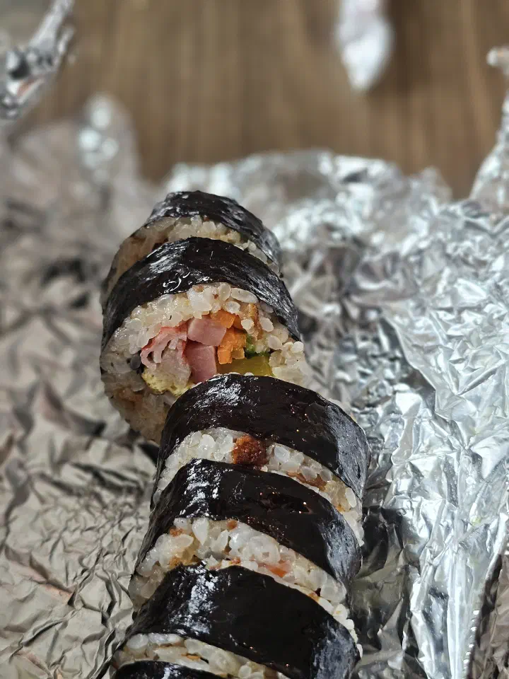 Close-up cross-section of Oneunjeong gimbap showing pickled radish, carrot, ham, and egg fillings