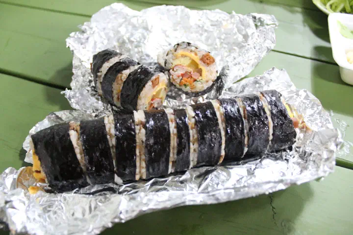 Two sliced Oneunjeong gimbap rolls on foil revealing the cross-section