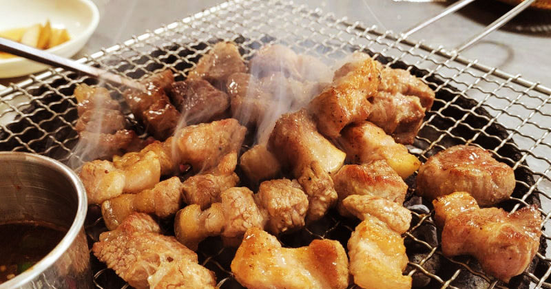 Jeju black pork belly grilling over charcoal at Jejugil Heukdwaeji Chamsut-gui