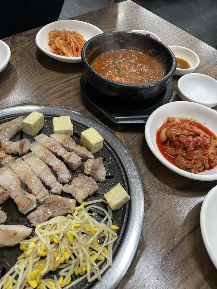 Tofu and bean sprouts grilling beside pork with a reduced pot of mel-jorim anchovy stew