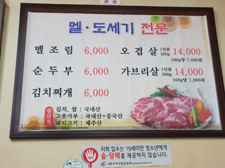 Menu board on the wall at Solji Sikdang listing mel-jorim, ogyeop-sal and gabri-sal prices