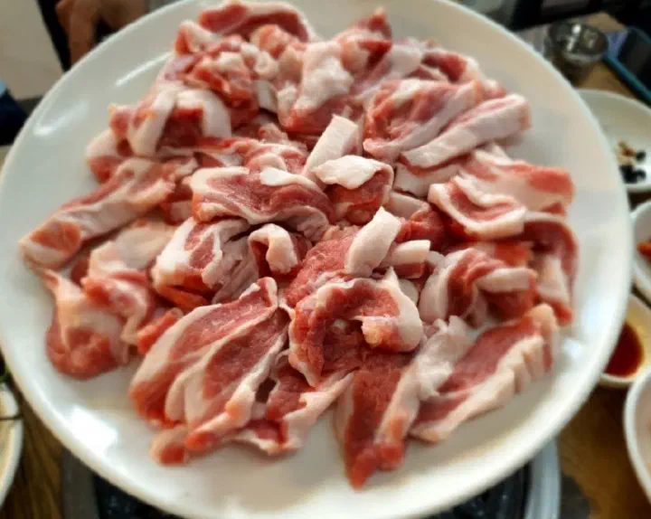 Plate of raw gabri-sal, a tender Jeju white pork collar cut, at Solji Sikdang