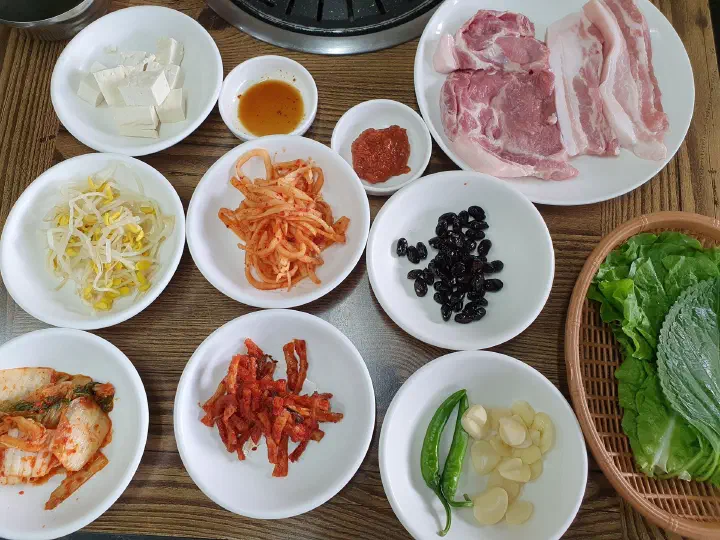 솔지식당 기본찬 두부 콩나물 무생채 김치 쌈채소와 생고기 한 상