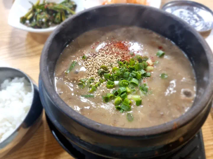 Gosari yukgaejang served boiling in an earthenware pot, topped with chili powder, sesame, and scallions