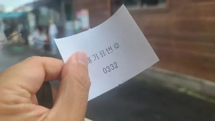 Paper waiting-number ticket pulled at the counter of Ujin Haejangguk&rsquo;s main building