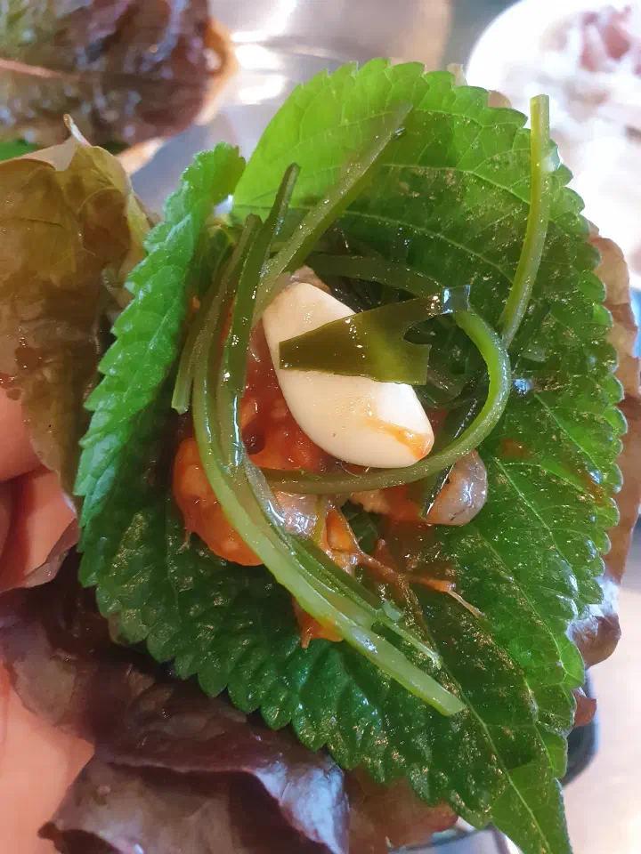 A piece of grilled eel wrapped in a perilla leaf at Dongbu Hoe Center