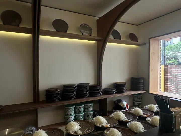 일월카츠 안국점 카운터에 준비된 양배추 접시와 선반의 그릇들