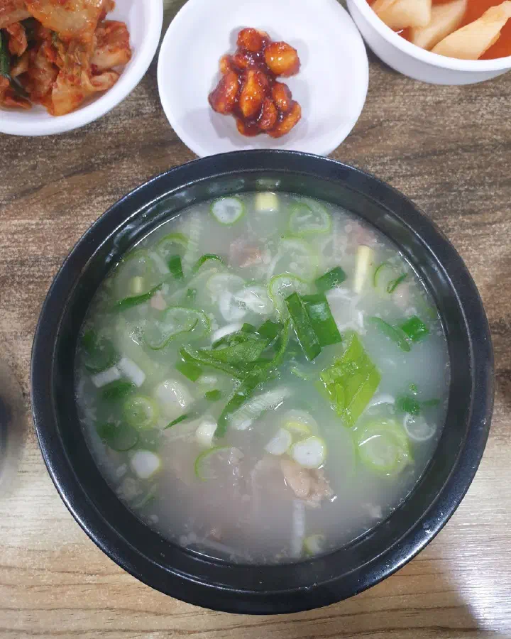 Top-down view of Daesungjip dogani-tang, a clear translucent broth topped with plenty of chopped green onion