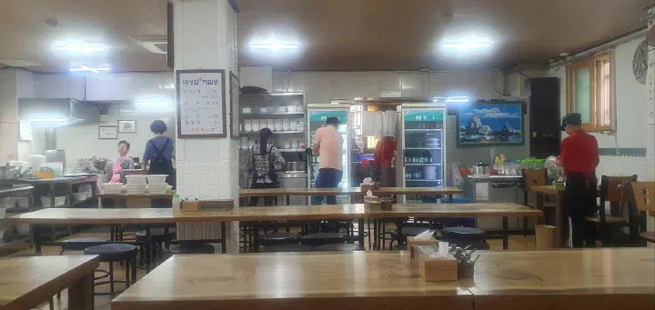 Tidy dining hall inside Daesungjip with wooden four-top tables