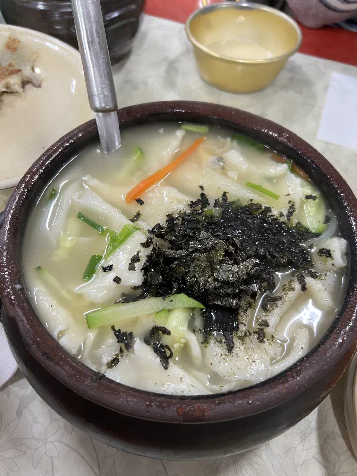 Close-up of Samcheongdong Sujebi hand-torn noodle soup in an earthenware pot topped with seaweed flakes