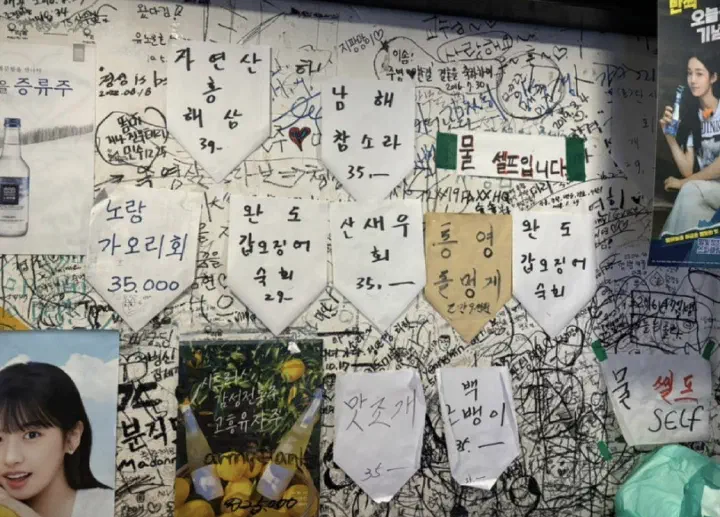 Handwritten Korean menu notes and a self-service water sign taped to the wall at Seochon Gyedanjip