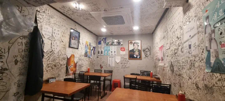 Interior of Seochon Gyedanjip with walls covered in customer graffiti and simple wooden tables