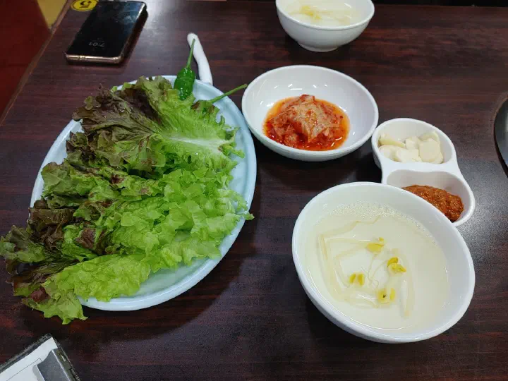 충무로쭈꾸미불고기 기본 상차림 상추 김치 마늘 쌈장과 차가운 콩나물국