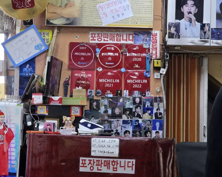 충무로쭈꾸미불고기 계산대 벽을 채운 미쉐린 빕구르망 스티커와 임영웅 포스터
