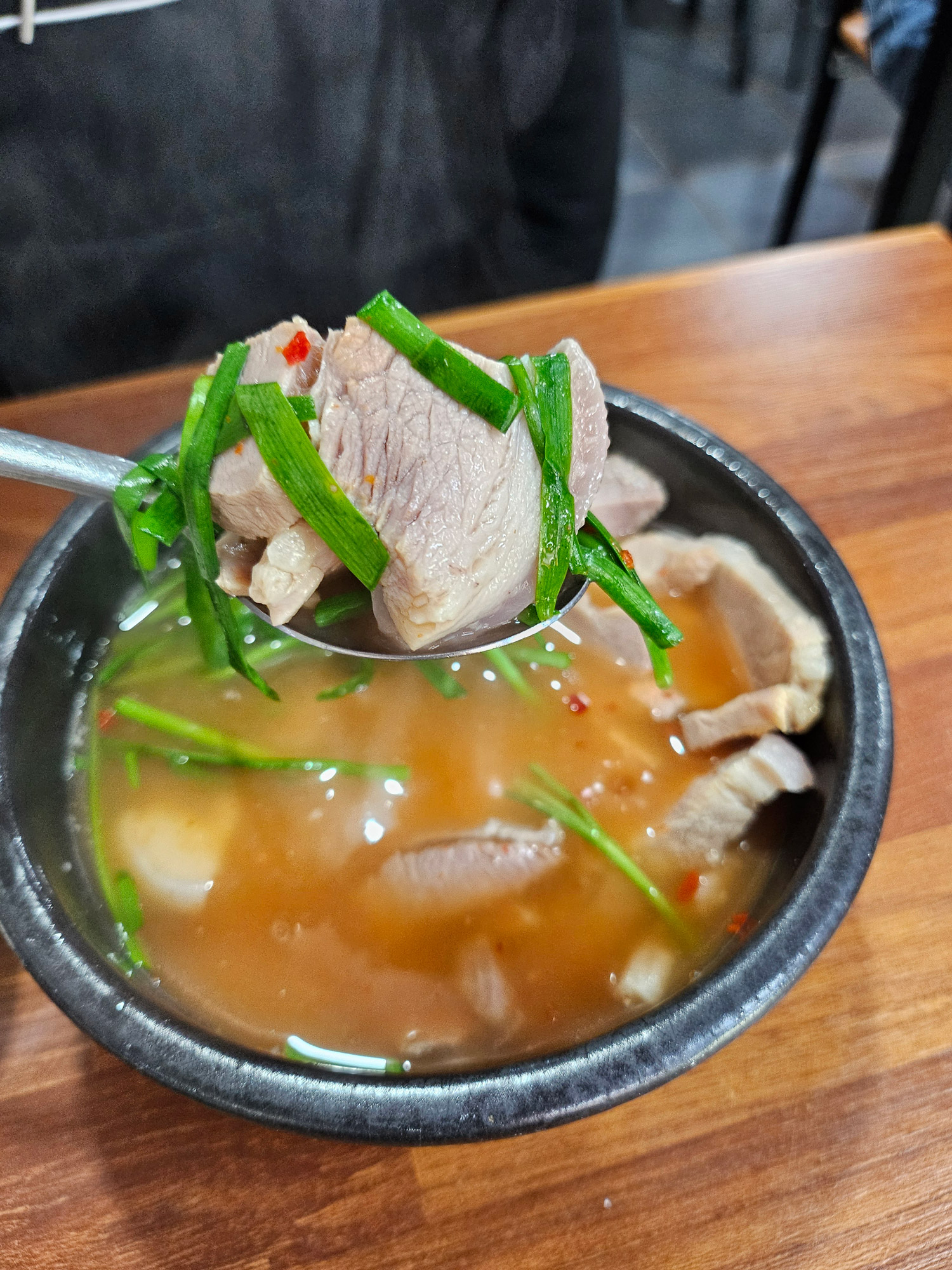 A thick slice of pork lifted out of the gukbap broth