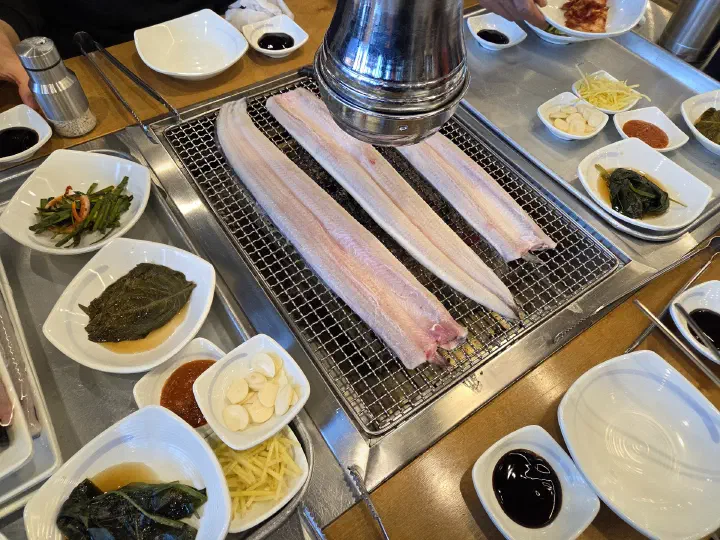 Whole freshwater eel fillets laid skin-side down on the hot charcoal grate