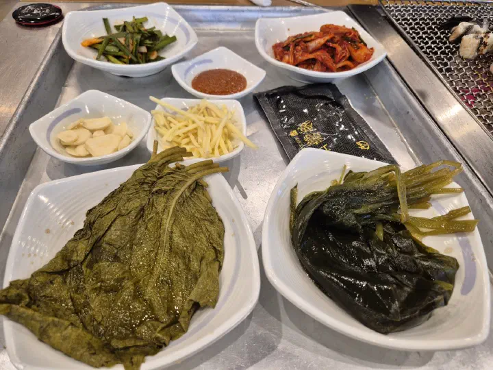 Banchan side dishes at Jangeoui Kkum including myeongi-namul, shredded ginger, garlic, and kimchi