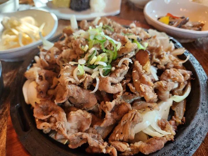 Close-up of Mokhyangwon charcoal-grilled pork with onions and scallions on the iron plate