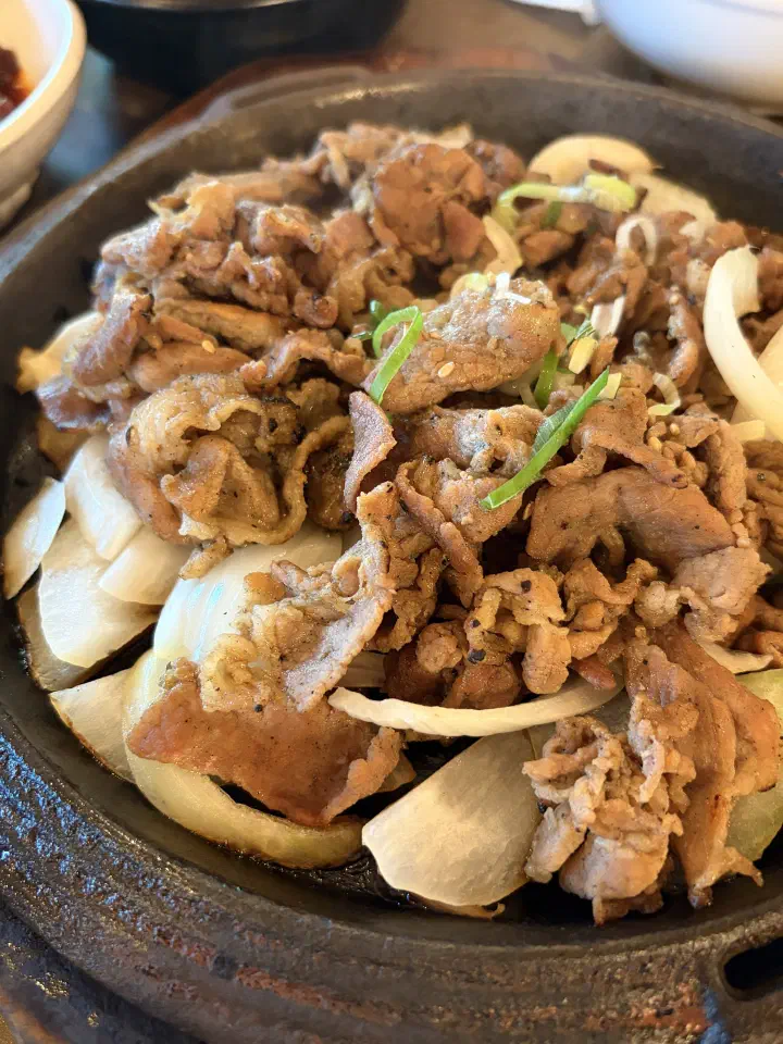 Thin slices of charcoal-grilled Korean pork shoulder over a bed of onions on a hot iron plate at Mokhyangwon