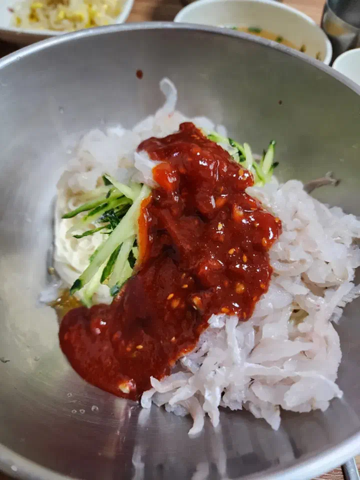 Adding sauce to the hoeguksu at Daegung Hoetown