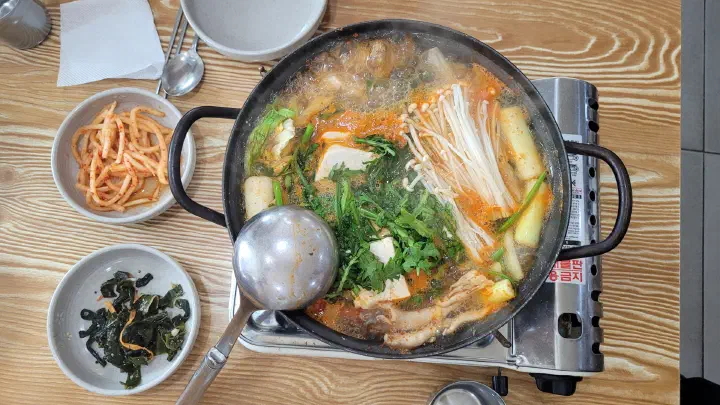 버너 위에서 끓는 백년옥 두부전골, 손두부와 쑥갓 팽이버섯이 푸짐하게 들어간 모습