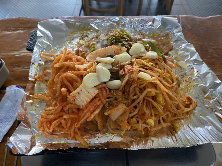 Marinated pork with radish, bean sprouts, kimchi and garlic set on the tabletop grill before cooking