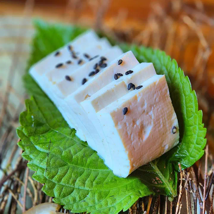 Sliced house-made onbiji tofu served on perilla leaves with black sesame seeds