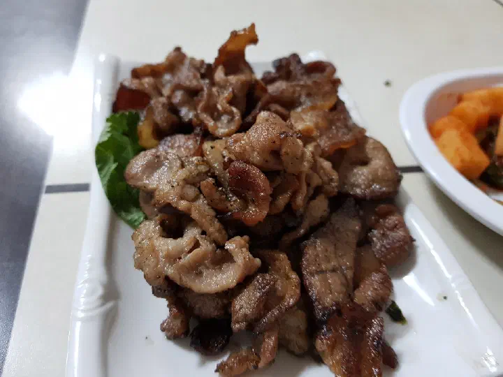 Daepae samgyeopsal, thin-sliced grilled pork belly served over lettuce