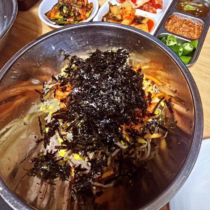 Korean bibimbap in a metal basin topped with seasoned laver before mixing