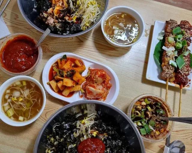 Kongnamul bibimbap set with bean sprout soup, side dishes and charcoal chicken skewers