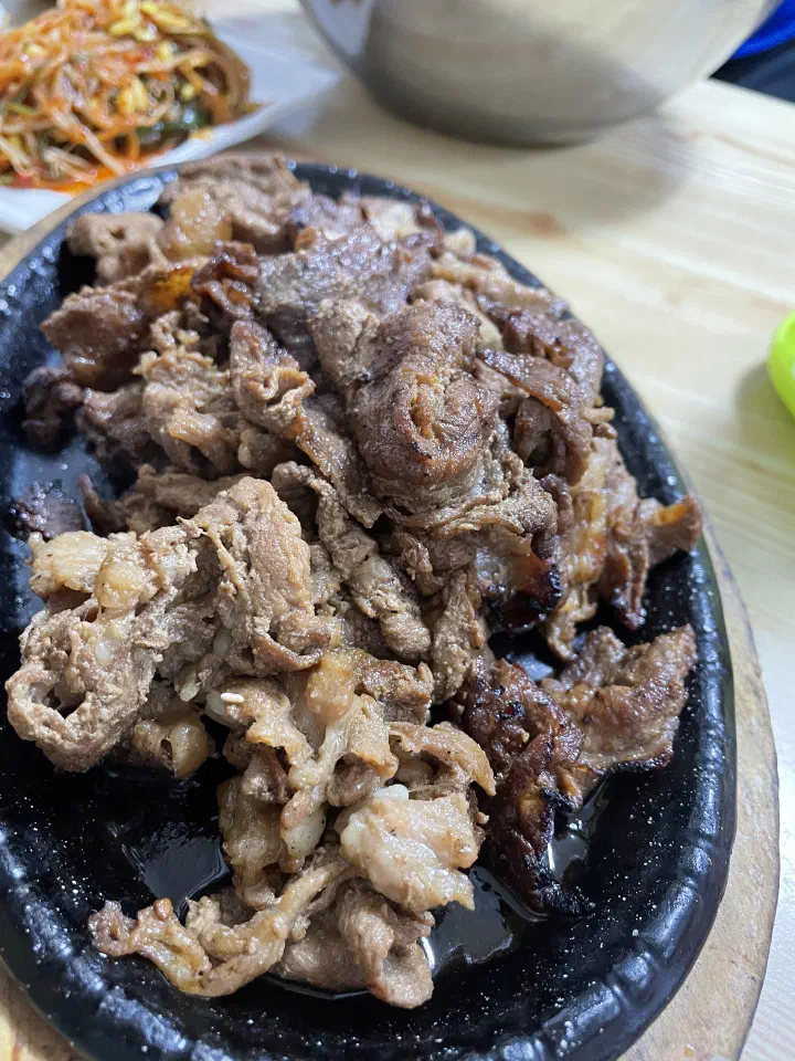 Close-up of thinly sliced charcoal-grilled marinated pork with a smoky char