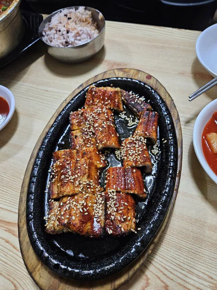 Charcoal-grilled conger eel served on a sizzling hot plate with a bowl of multigrain rice