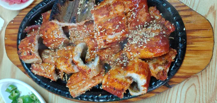 Portion of grilled conger eel finished with sesame seeds on a serving plate