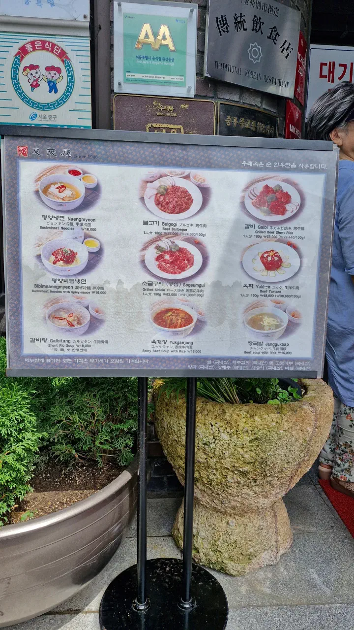 Menu board outside Woo Lae Oak in Euljiro showing Pyongyang naengmyeon, bulgogi and galbi with heritage restaurant plaques