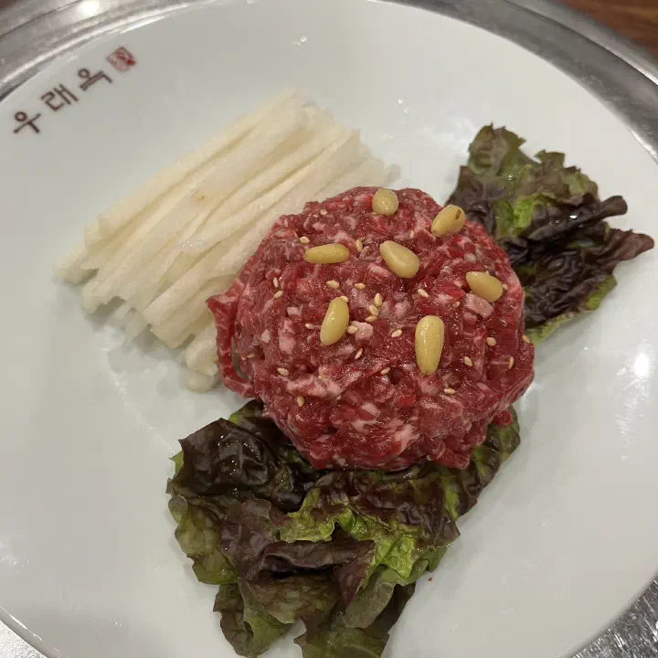 Hanwoo yukhoe beef tartare at Woo Lae Oak, topped with pine nuts and served with shredded pear and lettuce