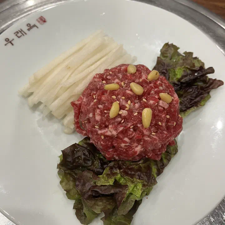 우래옥 접시에 담긴 한우 육회, 배채와 잣 그리고 상추가 곁들여진 모습