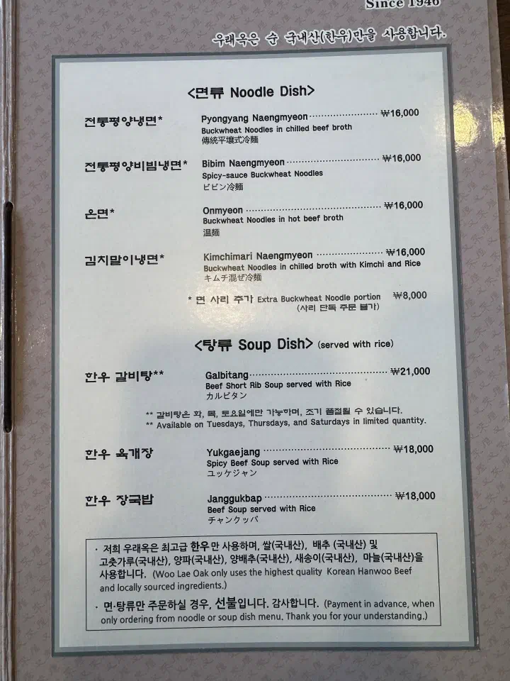 Woo Lae Oak indoor menu listing noodle and Hanwoo soup dishes with prices and a pay-in-advance notice