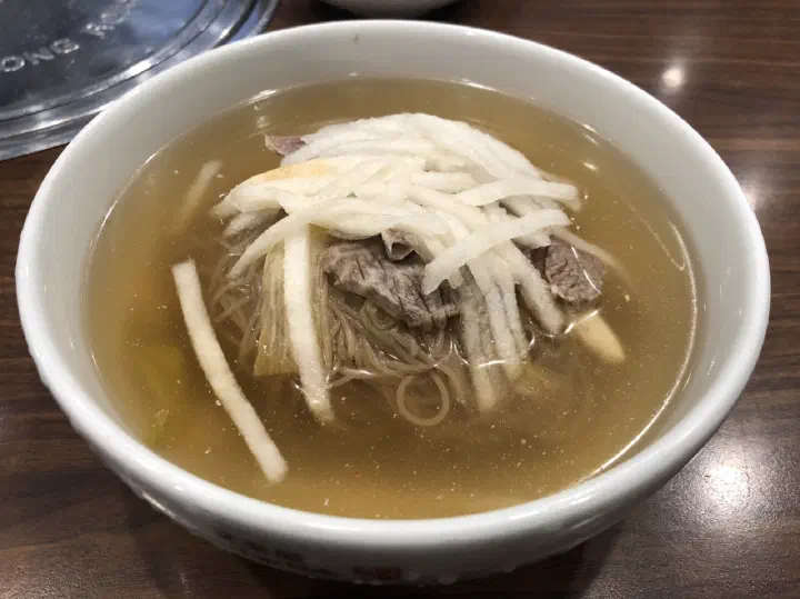 Close-up of Woo Lae Oak Pyongyang naengmyeon, clear Hanwoo beef shank broth with buckwheat noodles, pyeonyuk and pear