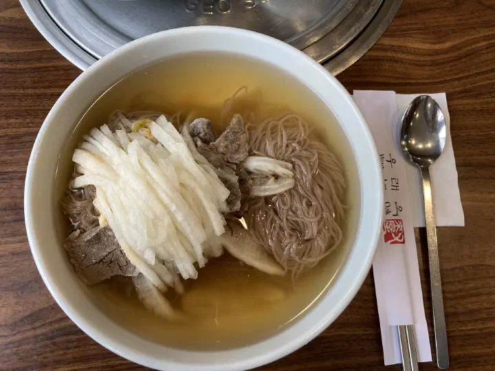 Top-down view of traditional Pyongyang naengmyeon at Woo Lae Oak with buckwheat noodles, sliced beef and shredded pear