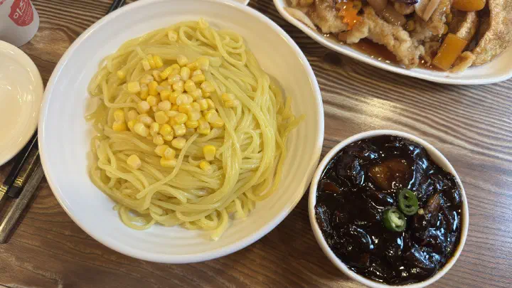 Yeonghwaru gochu-ganjjajang before mixing, noodles topped with sweet corn beside the black-bean sauce