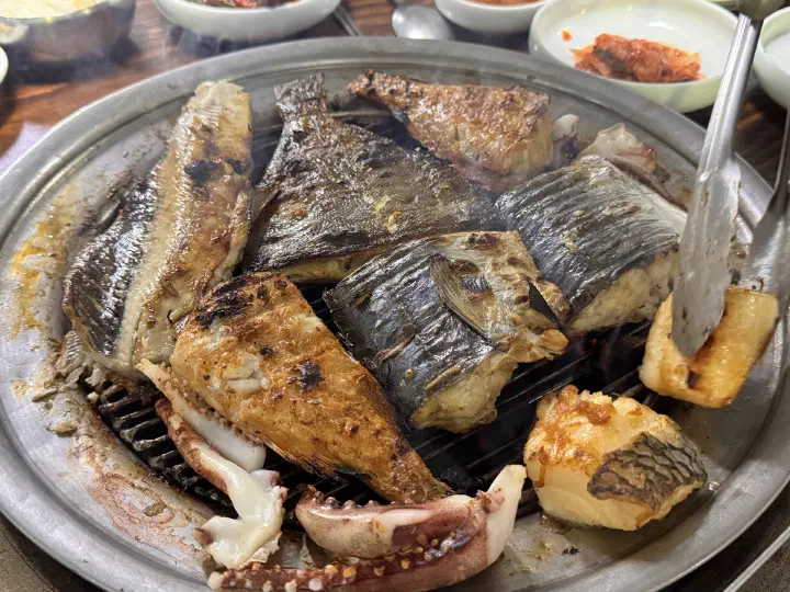 겉은 노릇하고 속은 촉촉하게 숯불에 구워진 88생선구이 고등어와 오징어 클로즈업