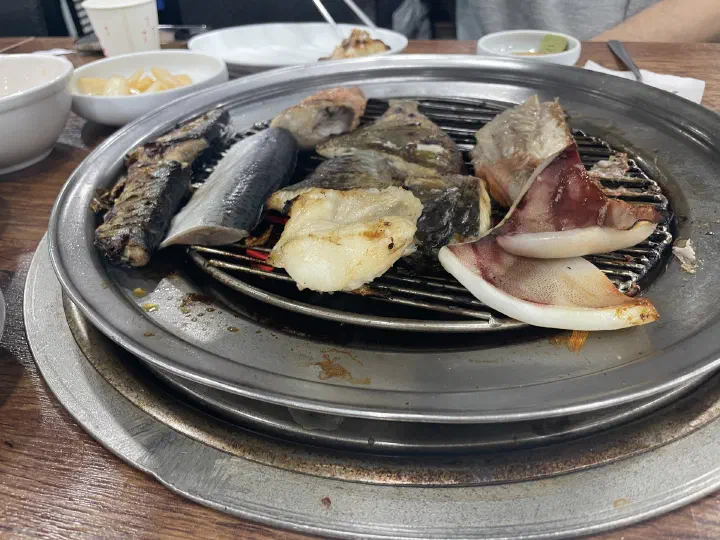숯불 화로에서 함께 구워지는 88생선구이 청어와 메로, 오징어