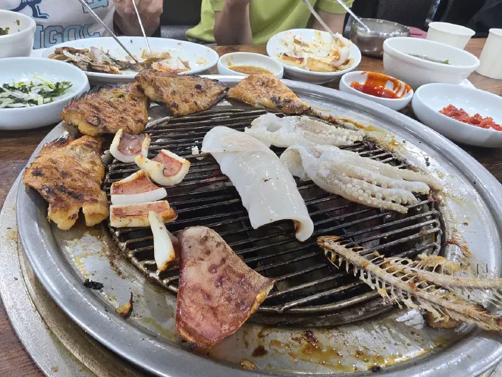 88생선구이 숯불 석쇠 위에서 통째로 구워지는 오징어와 다 발라낸 생선뼈