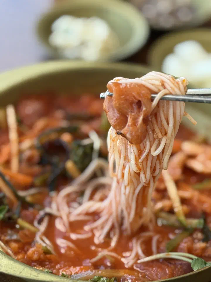 Thin somyeon noodles lifted with chopsticks from the chilled mulhoe broth at Chungchosoo Mulhoe