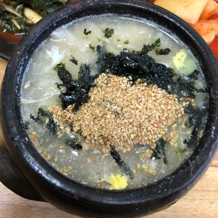 Gamja ongsimi potato dumpling soup in an earthenware pot topped with seaweed flakes and sesame at Gamnamujip in Sokcho