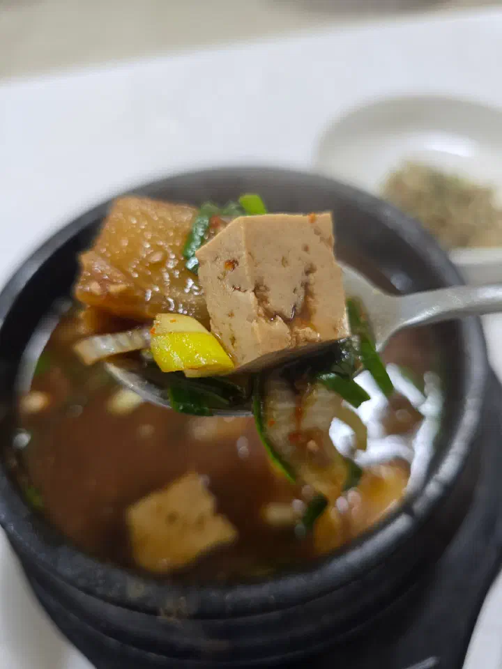 A spoonful of tofu and squash lifted from the doenjang-jjigae